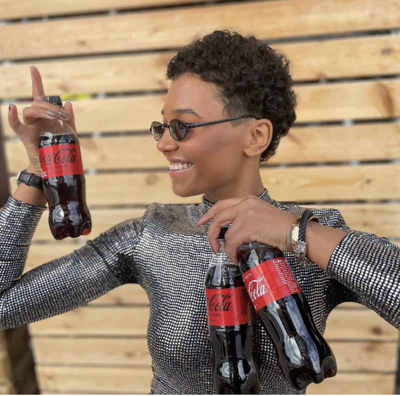 Photo d'une jeune femme tenant plusieurs petites bouteilles de coca cola