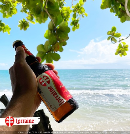 une main tenant une bière lorraine devant la mer