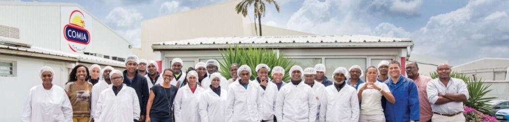 Photo de groupe du personnel de comia posant tout sourire devant les locaux de l'entreprise