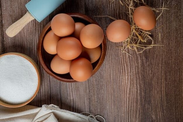 Oeufs frais posé sur une table avec du sucre et un rouleau de patisserie